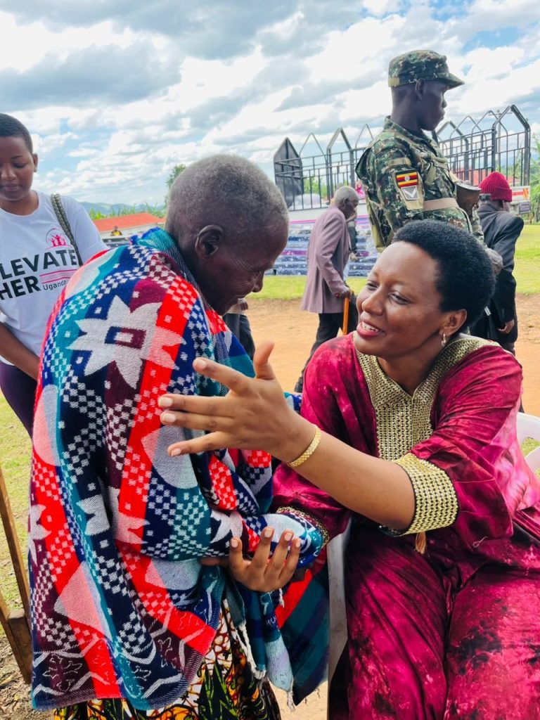 Loice Natukunda embraces an elderly woman wrapped in a new bedcover