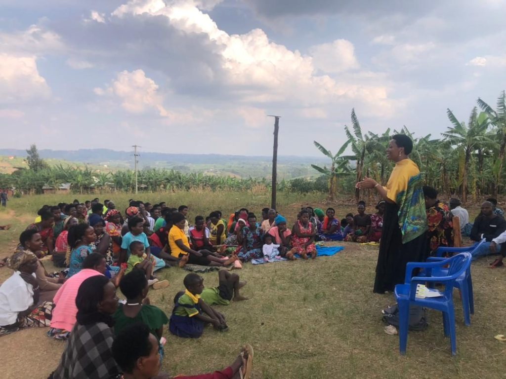 A speaker addresses women seated on the grass