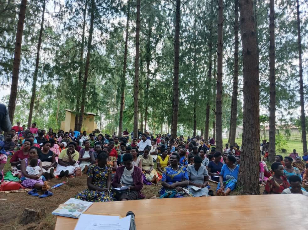 A large crowd of women gathered under the trees