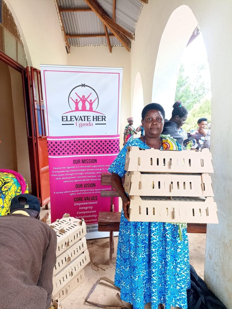 A woman holds boxes of chicks beside an Elevate Her banner
